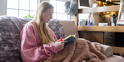 Student sitting and reading in dorm.