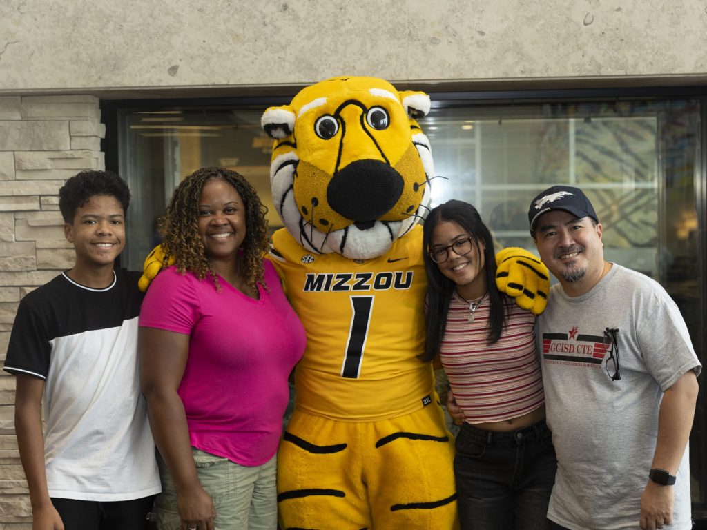 a mizzou family poses with truman the tiger in the mu student center